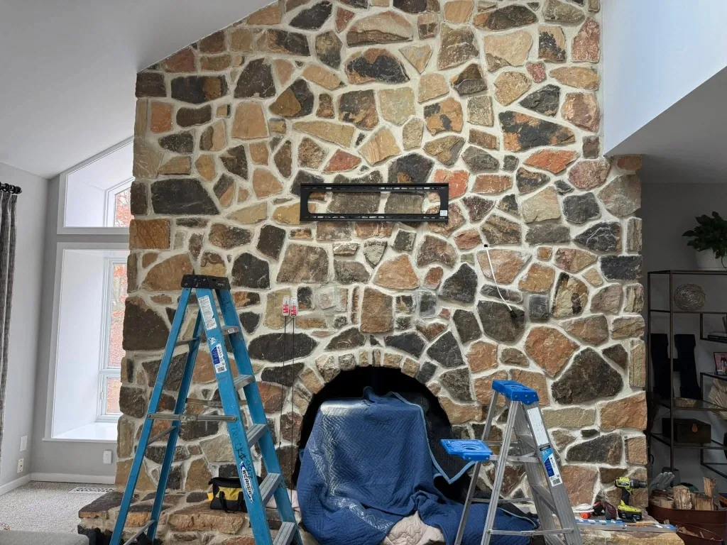 Before TV fireplace mounting in Green Bay – TV sitting on a media console below a brick fireplace